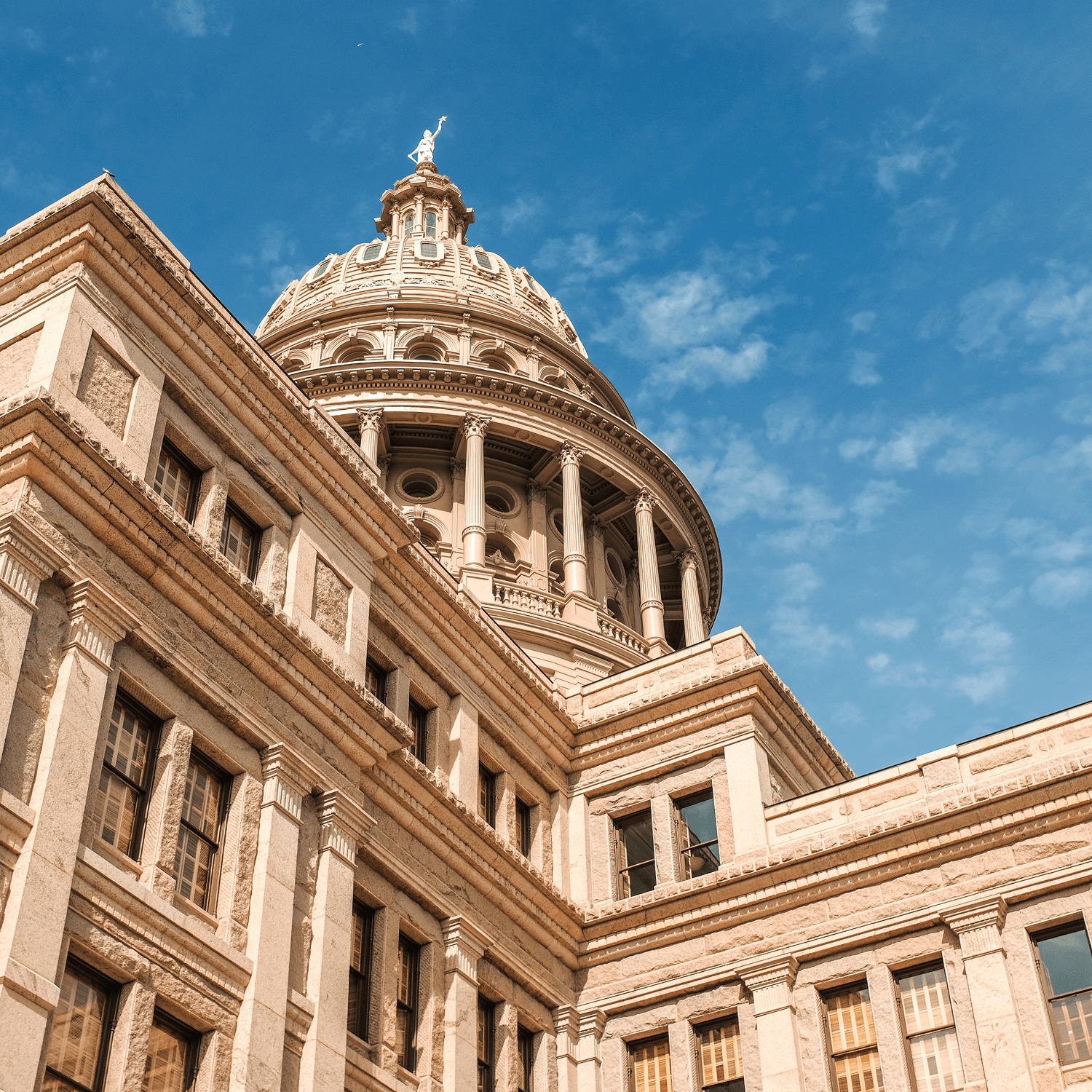 Close-up view of a historic stone building with a large dome and column details, set against a bright blue sky with scattered clouds—an architectural landmark where history converges with modern responsibilities, such as responding to an EEOC charge.