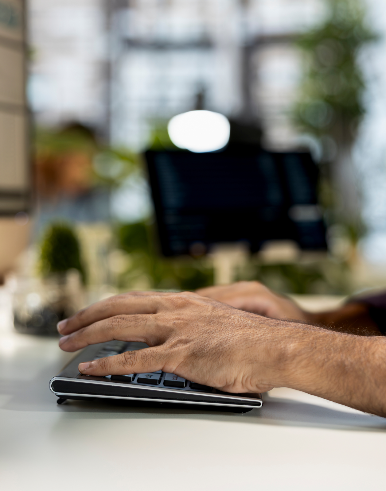 A person’s hand using a computer mouse next to a laptop on a desk with a blurred monitor and office background, evoking the professional environment of a full service law firm.